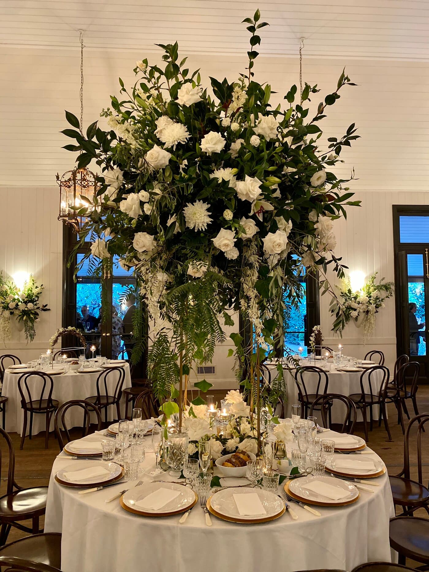 Reception detail at Jaspers Berry — a tall white floral centrepiece on the round dinner table